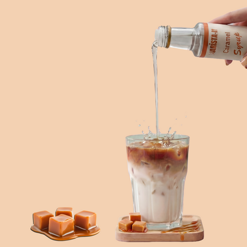 Caramel syrup being poured into a glass of iced coffee with caramels on a beige background