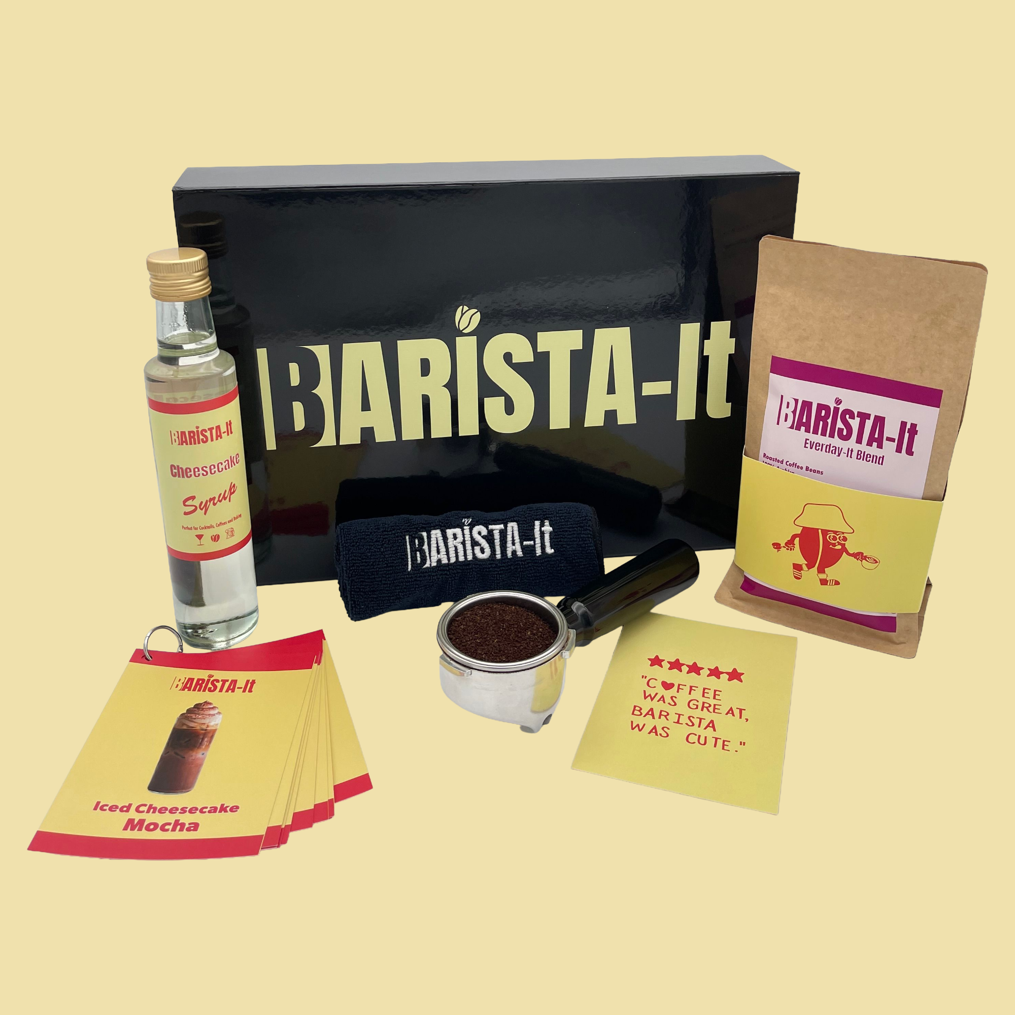 Collection of Cheesecake Barista-it Coffee products including a black box, Syrup bottle and recipe cards.