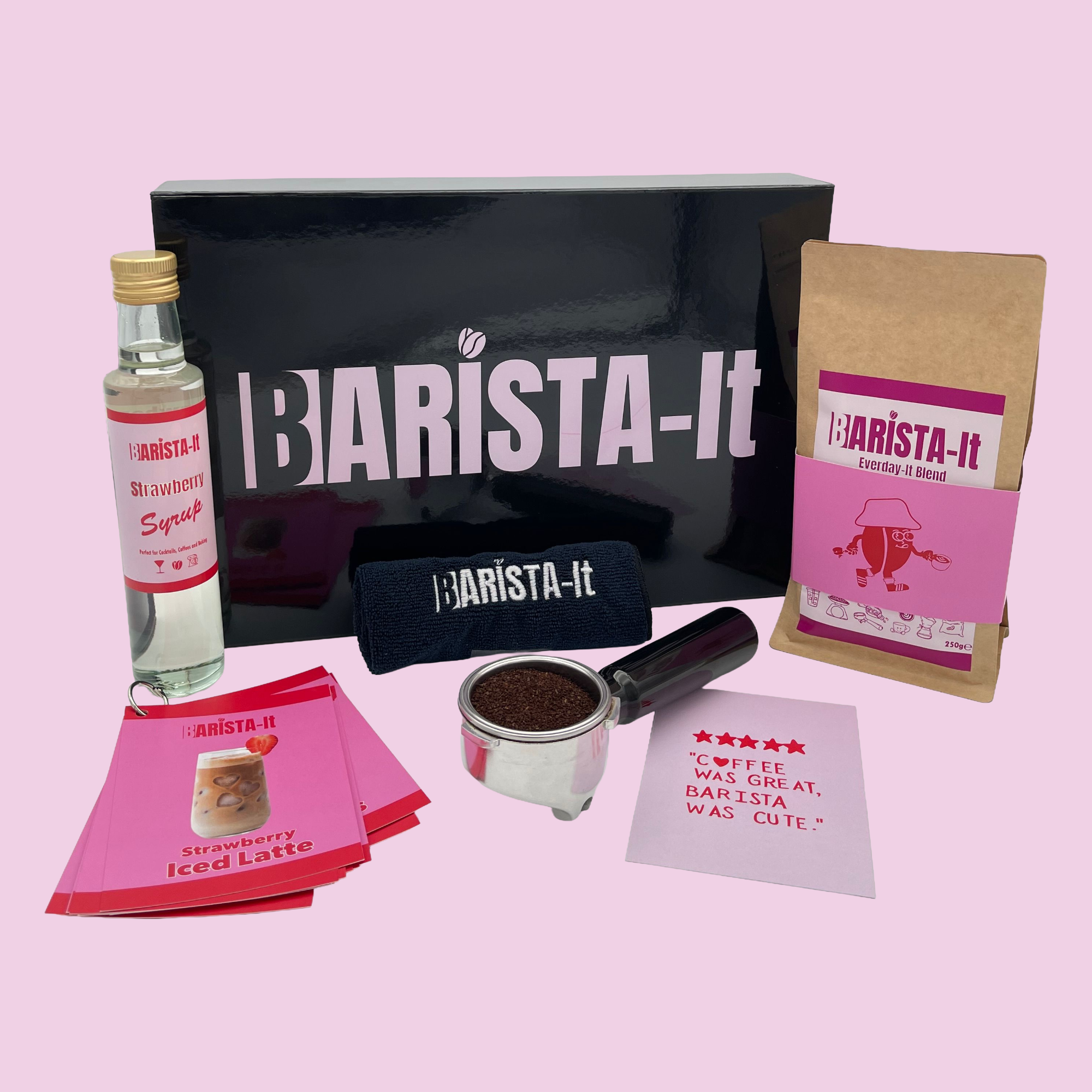 Collection of Strawberry Barista-it Coffee products including a black box, Syrup bottle and recipe cards.