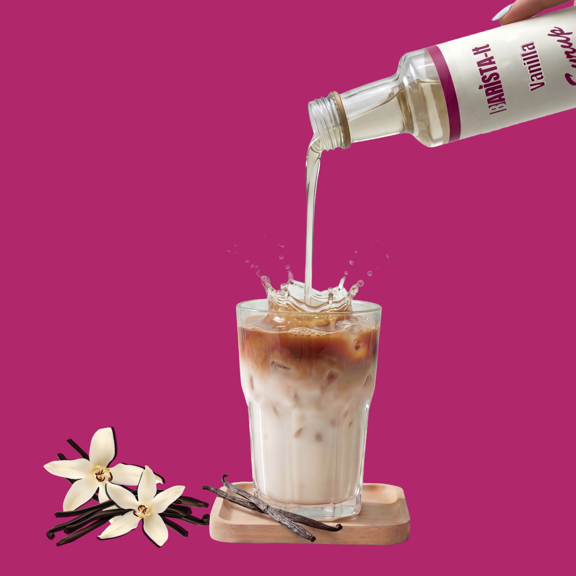 Vanilla syrup being poured into a glass of iced coffee with vanilla beans and flowers on a pink background.